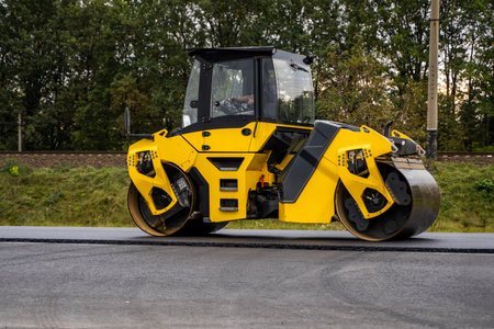 Yellow road roller compacting fresh asphaltの写真素材