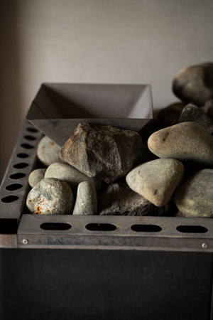 Smooth and rough sauna stones stacked in a metal heater close-upの写真素材