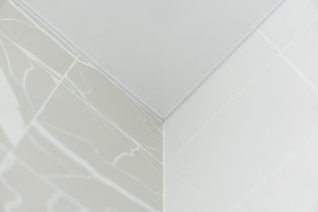 Minimalistic white corner of ceramic tile wall with glossy finish and light marble textureの写真素材