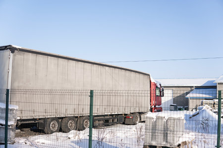 Full view of long trailer truck parked in logistics facility yard covered with snowの写真素材