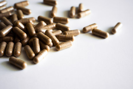 Brown dietary supplement capsules scattered on clean white backgroundの写真素材