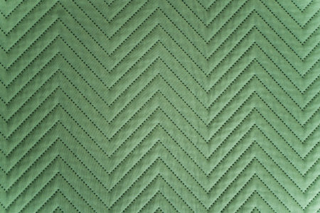 Close-up of quilted green fabric with zigzag stitched pattern in soft lightingの写真素材