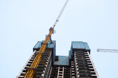 Low-angle view of skyscraper and tower crane under construction