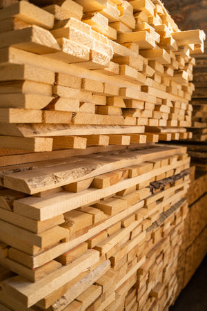 Vertical lumber pile in workshop lit with warm afternoon sunlightの写真素材