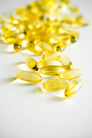 Close-up of shiny fish oil capsules scattered on white surfaceの写真素材