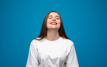 Laughing young woman with long brown hair in white t-shirt