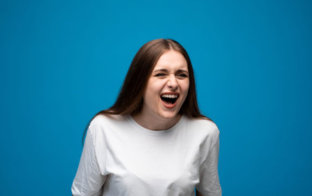 Laughing young woman with long brown hair enjoying sincere joy