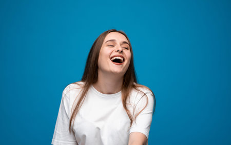 Laughing young woman with long brown hair in white t-shirt expressing joy