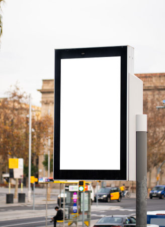 Blank vertical digital billboard with white screen mockup advertising template standing on a city street corner, offering space for urban marketing campaigns and new product promotionの写真素材