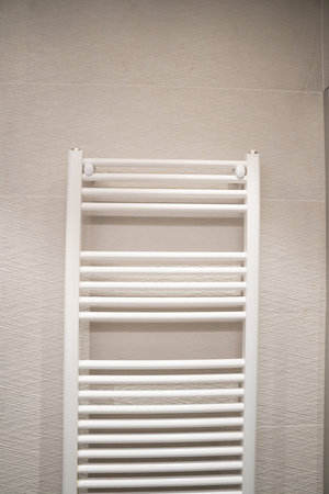 White bathroom towel rail heater providing warm comfort in a modern home interior, ensuring ready-to-use dry towels in a contemporary hotel or residential spaceの写真素材