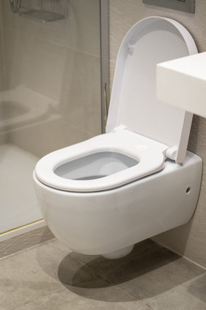 White ceramic wall-mounted toilet with an open lid in a modern bathroom, emphasizing cleanliness,...