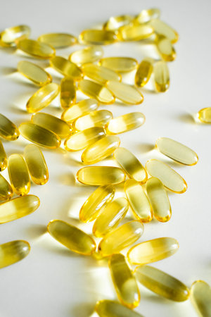 Yellow omega-3 softgel capsules on white background, fish oil supplements