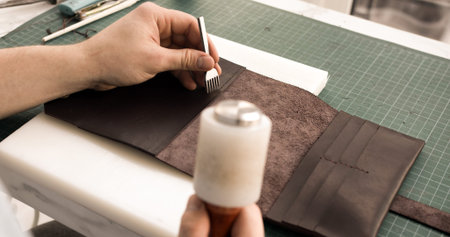 Leather crafting process with awl and mallet while making handmade wallet