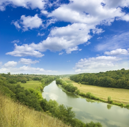 Green meadow under blue sky with cloudsの写真素材