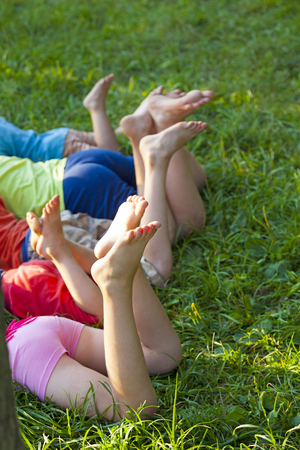 Happy children lying on green grass outdoors in spring parkの写真素材