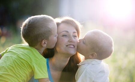 Happy mother with two children in garden. Happy young boys kisses mother.の写真素材
