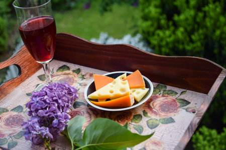 a glass of red wine with cheese on the balcony of the house in front of the gardenの写真素材