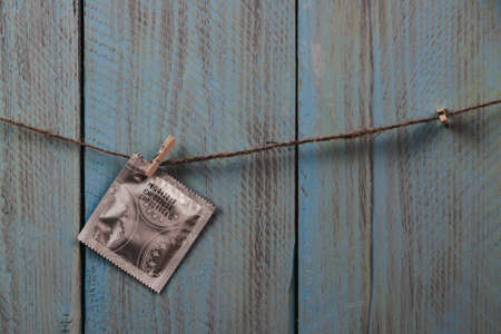 Condom in package hanging on the rope against blue wooden rustic background. Copyspace. Concept of love, Saint Valentines Dayの写真素材