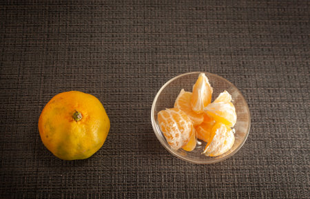 Peeled fresh tangerines on a black background. Nearby are mandarin slices. Seasonal citrus fruits,...