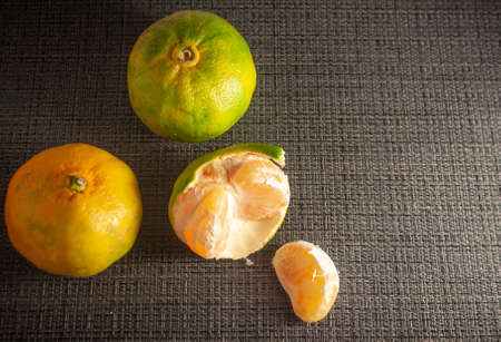 Peeled fresh tangerines on a black background. Nearby are mandarin slices. Seasonal citrus fruits, natural healthy food. Close-upの写真素材
