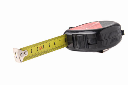 Construction tape measure in black, lying on its side with an open tape. Isolated on a white...