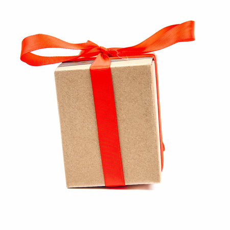 Square cardboard box tied with red ribbon isolated on a white background. Close-upの写真素材