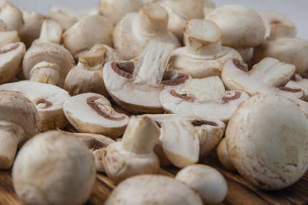 Fresh whole and sliced champignons on a dark board close-up. Selective focusの写真素材