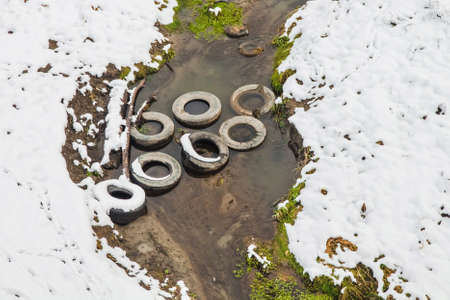 Old car tires blocked the stream that feeds the river. Environmental problemsの写真素材