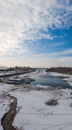 Backwater on the river with a ship repair shop on the shore. Winter landscape