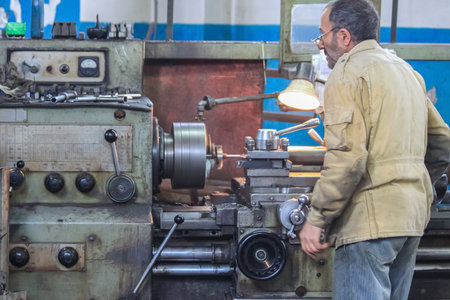 Krasnodar, Russia - October 10, 2011: The turner works on an old battered lathe. Industrial...