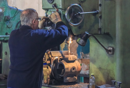 A man works on an industrial drilling machine