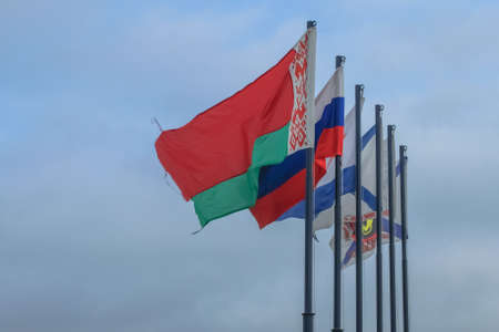 Belarusian, Russian and St. Andrews flags are flying against the blue skyの写真素材