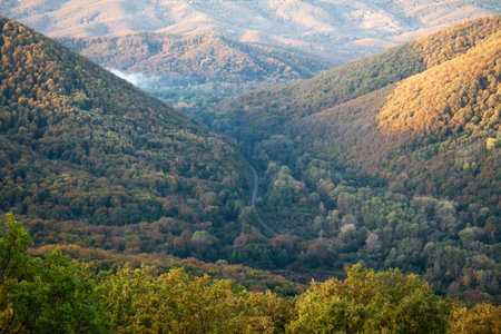 Mountain valley through which the railway passes. Autumn landscape in the rays of the rising sun