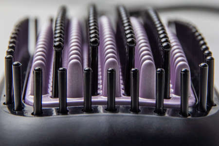 Black and purple bristles of an electric thermal brush for straightening hair on macro photography. Selective focus. Background imageの写真素材