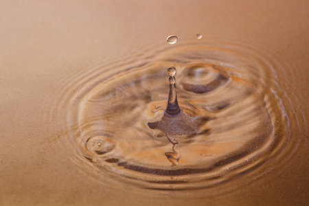 A drop of rain falls on the surface of the water, through which the brown sand shines through. Background image. Close-upの写真素材