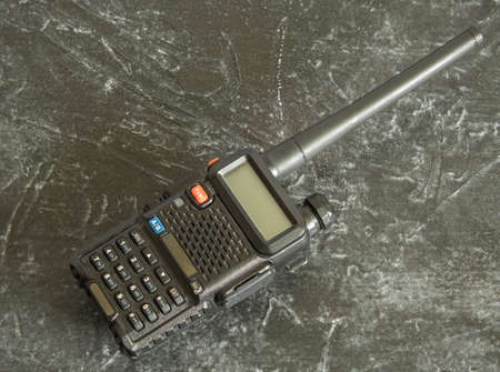 A black portable radio station on a dark concrete background. It is popular with security guards, builders, road builders, hunters, tourists and fishermenの写真素材