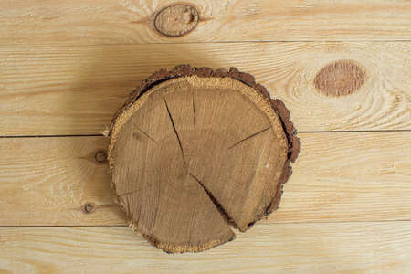 On a wooden background lies a round section of oak wood with cracks. Top viewの写真素材