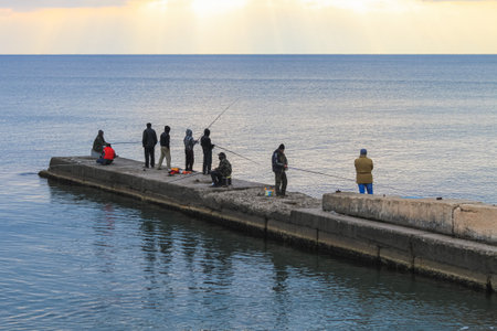 Sudak, Republic of Crimea, November 5, 2011: Fishermen on a concrete pier catch fish on a fishing rod in the Black Sea at sunset dlyのeditorial素材