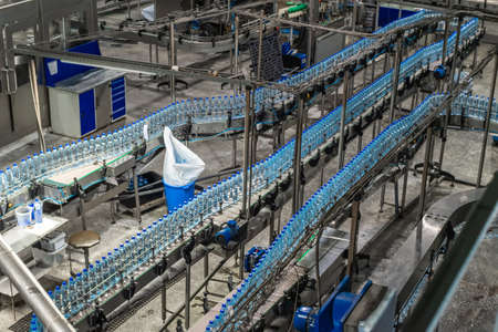 Conveyor line with blue plastic drinking water bottles in a mineral water production shop. Food productionの写真素材