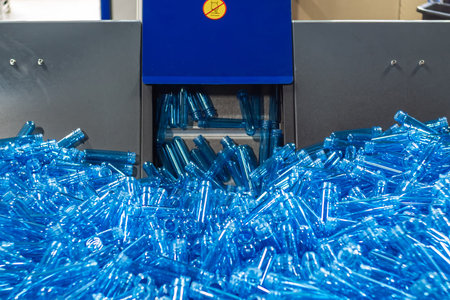 Blue plastic preforms for one and a half liter bottles in a storage hopper and conveyor belt. Food...