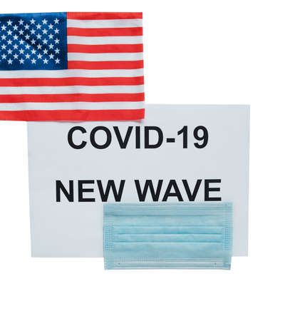 Sheet with inscription:  new wave, medical mask and US flag. Isolated on a white background. Concept of the next wave of infections in the United Statesの写真素材