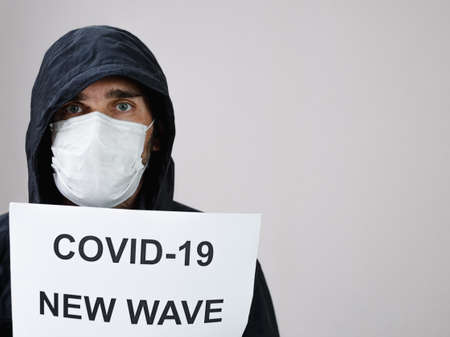 A man of Caucasian nationality wearing black clothes and a hood. There is a medical mask on his face.の写真素材