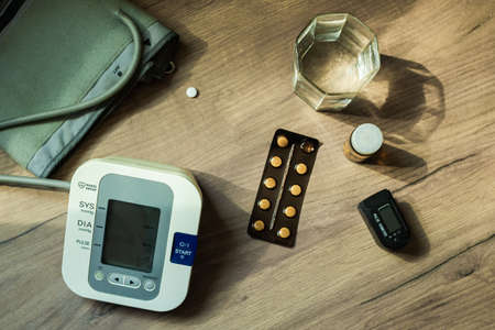 On the table there are pills, a blood pressure measuring device, a glass of water and an oxyometer. An elderly person's kit. Top view. Health Conceptの写真素材