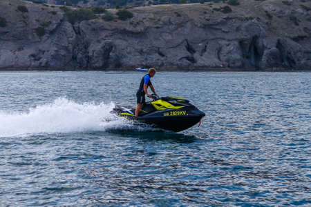 A man on a jet ski against the backdrop of a rocky shore. Republic of Crimea, Sudak, July 27, 2013のeditorial素材