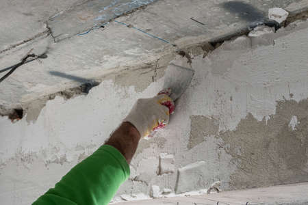 Close-up of a man applying plaster to a wall with a small trowel. The concept of room finishingの写真素材