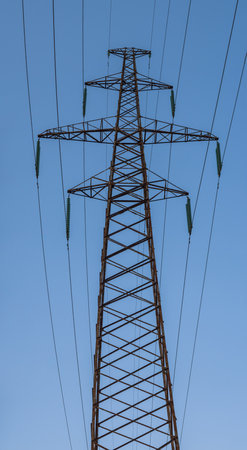 Tall metal construction of a high-voltage power line pylon against a blue sky background. Panoramic photoの写真素材