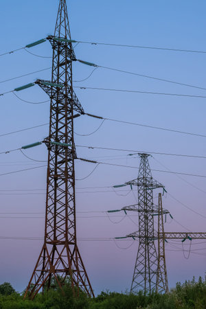 Pylons and high-voltage power lines at sunset. Industrial landscape. The concept of the energy...
