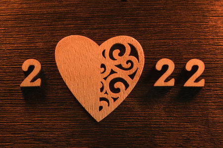 On a dark textured wooden background, the number 2022 is laid out in numbers, where instead of 0 there is a heart. Happy New Year 2022の写真素材