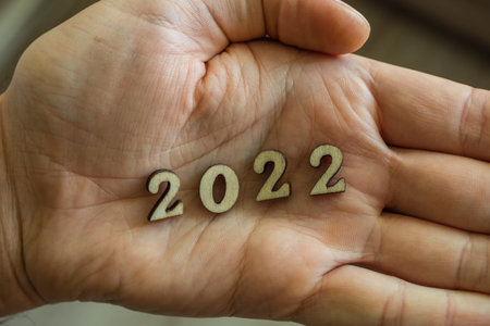 Close-up of a man's palm with wooden numbers 2022. Minimalism and ecology as a way of life. The...