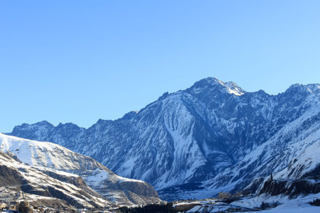 A snowy mountain range against a clear blue sky. Morning mountain scenery